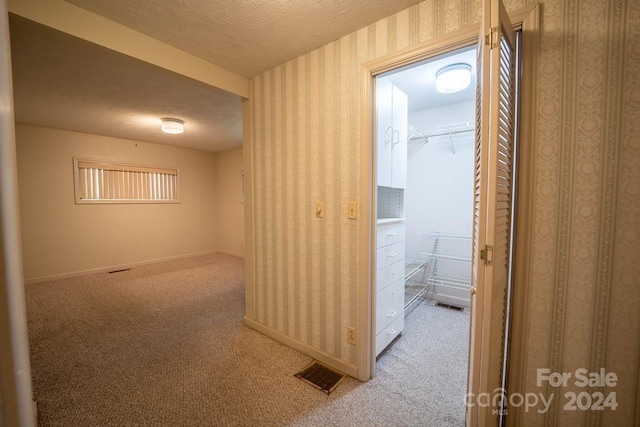 hall featuring light colored carpet and a textured ceiling