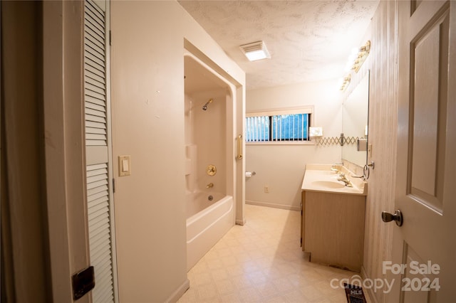 bathroom featuring washtub / shower combination, a textured ceiling, and vanity