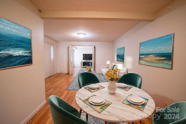 dining space with a textured ceiling and light hardwood / wood-style flooring