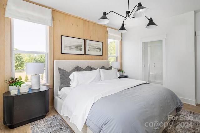 bedroom with light hardwood / wood-style flooring, multiple windows, and a chandelier