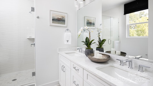 full bathroom with double vanity, baseboards, a sink, and a stall shower