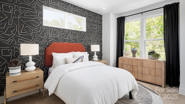 bedroom featuring wallpapered walls, an accent wall, and wood finished floors