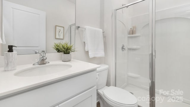 bathroom with a stall shower, vanity, and toilet