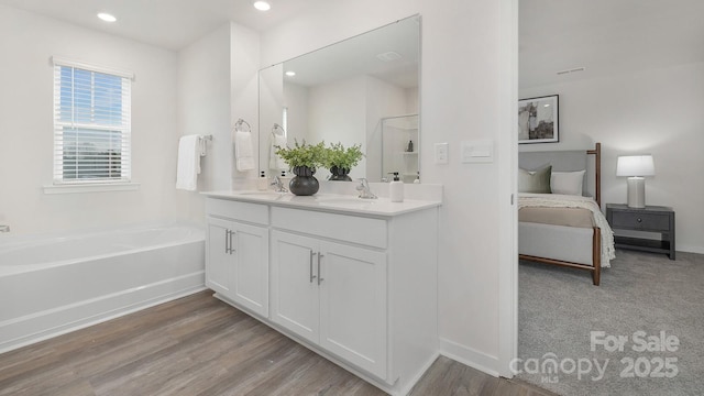 ensuite bathroom with double vanity, connected bathroom, wood finished floors, a shower stall, and a sink