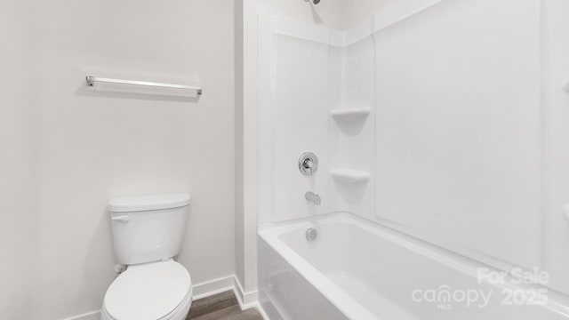 bathroom featuring baseboards, shower / bathing tub combination, toilet, and wood finished floors