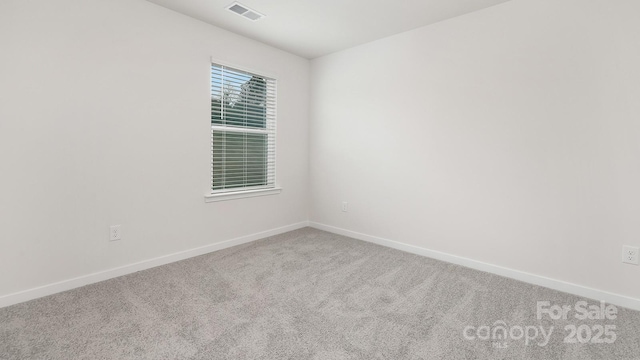 carpeted spare room featuring visible vents and baseboards