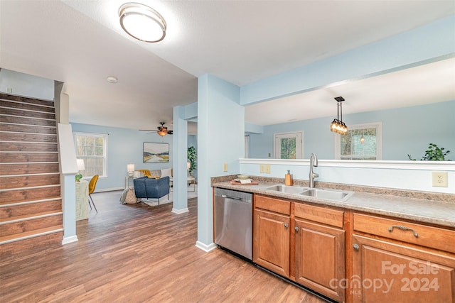 kitchen with light wood-type flooring, sink, hanging light fixtures, ceiling fan, and stainless steel dishwasher