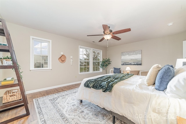 bedroom featuring light wood-type flooring, multiple windows, and ceiling fan