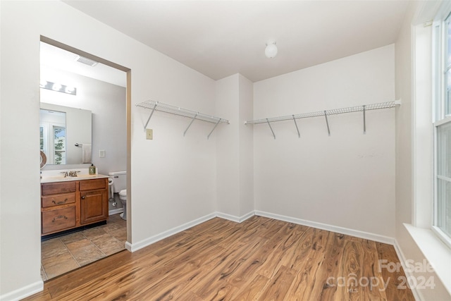 walk in closet with light wood-type flooring and sink