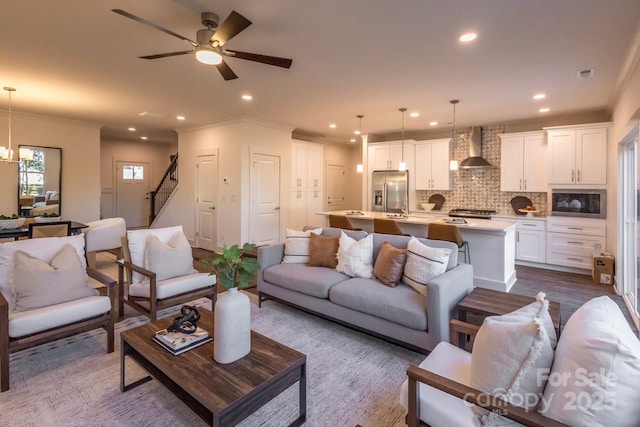 living room with ceiling fan with notable chandelier, dark hardwood / wood-style floors, and crown molding