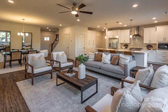 living room with dark hardwood / wood-style floors, ornamental molding, and ceiling fan with notable chandelier