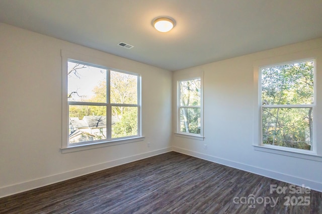 empty room with dark hardwood / wood-style floors and a healthy amount of sunlight