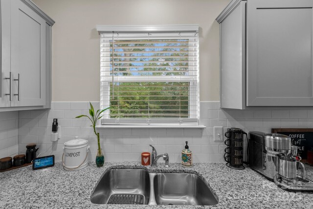 kitchen with gray cabinets, light stone countertops, and sink