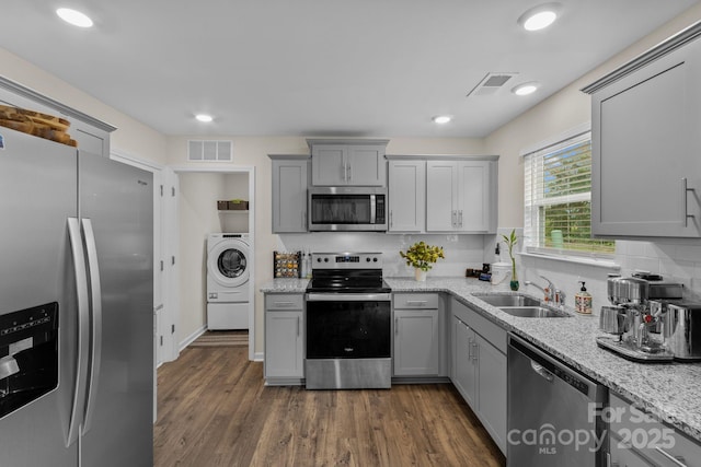 kitchen with gray cabinetry, sink, dark hardwood / wood-style flooring, stainless steel appliances, and washer / clothes dryer