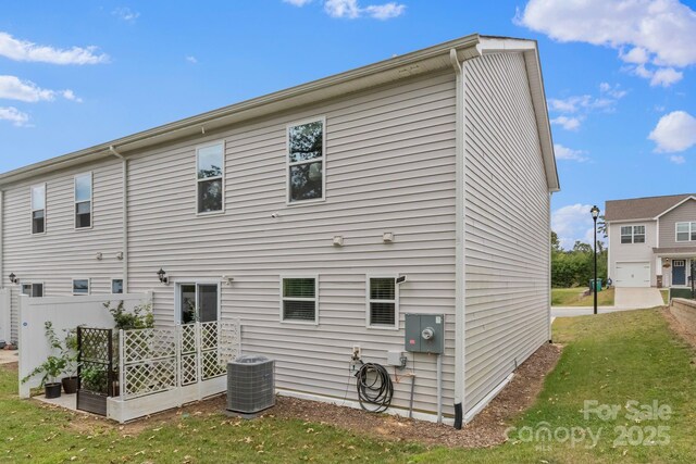 rear view of house with cooling unit and a lawn