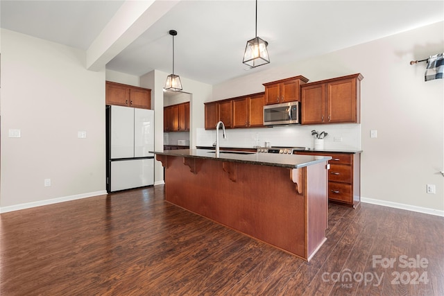 kitchen featuring sink, a breakfast bar, dark hardwood / wood-style floors, appliances with stainless steel finishes, and a center island with sink