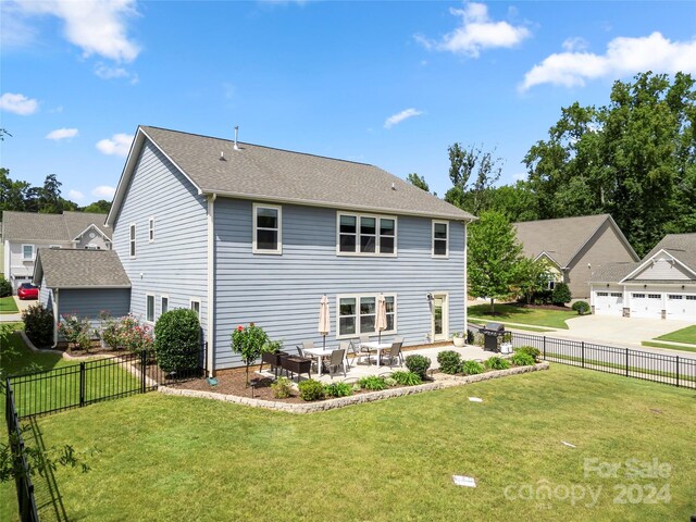 rear view of house with a lawn, a garage, and a patio area