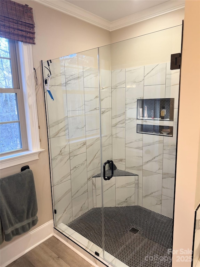 bathroom with hardwood / wood-style floors, a shower with shower door, and crown molding