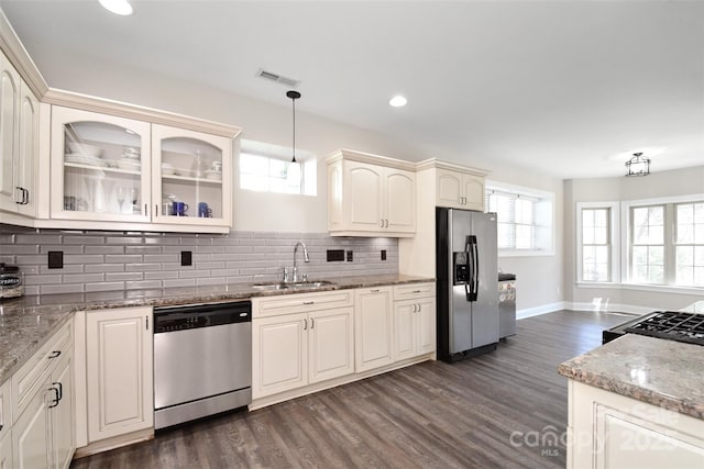 kitchen featuring light stone countertops, appliances with stainless steel finishes, dark hardwood / wood-style flooring, sink, and pendant lighting