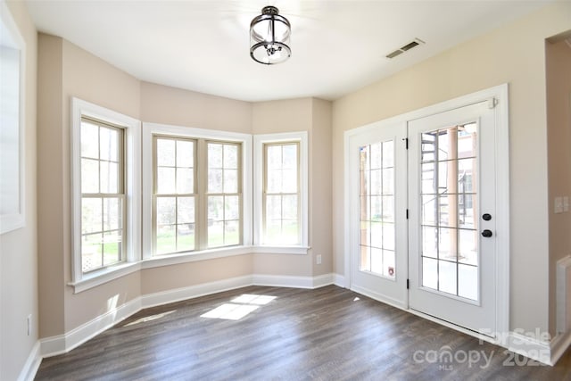 doorway to outside with dark hardwood / wood-style flooring, an inviting chandelier, and a wealth of natural light