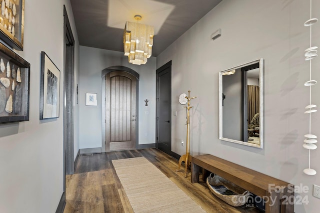 foyer featuring dark wood-type flooring and a chandelier