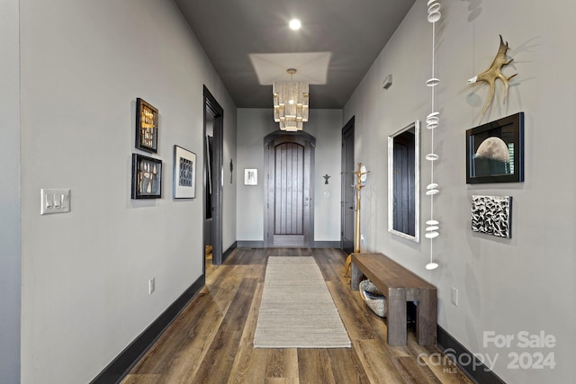 entryway with dark wood-type flooring and an inviting chandelier