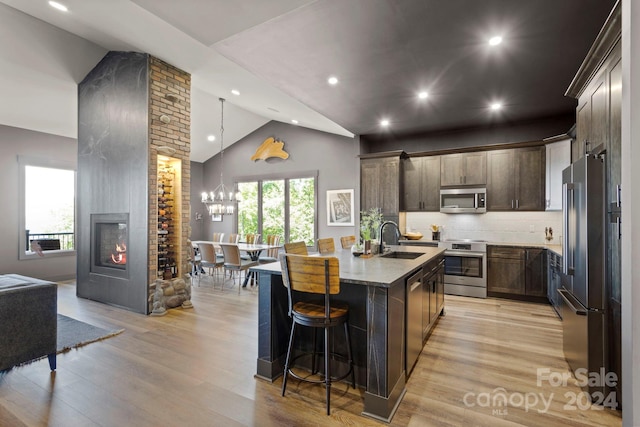 kitchen with a kitchen island with sink, appliances with stainless steel finishes, light hardwood / wood-style flooring, and sink