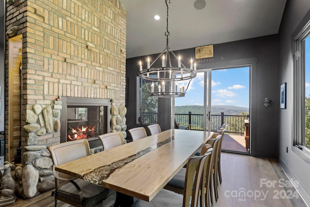 dining space featuring a mountain view, an inviting chandelier, wood-type flooring, and a fireplace