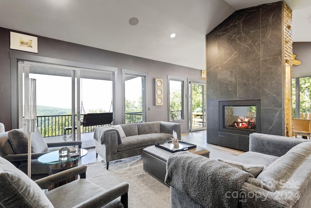 living room featuring plenty of natural light, a tiled fireplace, and vaulted ceiling