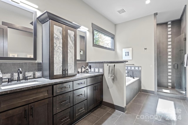 bathroom featuring plus walk in shower, tile patterned flooring, tasteful backsplash, and vanity