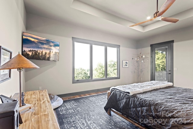 bedroom featuring ceiling fan, wood-type flooring, multiple windows, and access to outside