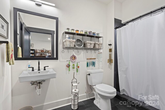 bathroom featuring a shower with curtain, toilet, sink, and tile patterned floors