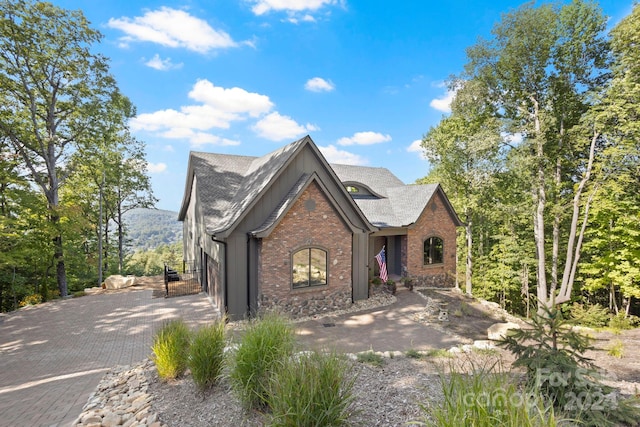 view of front facade featuring brick siding, decorative driveway, and roof with shingles