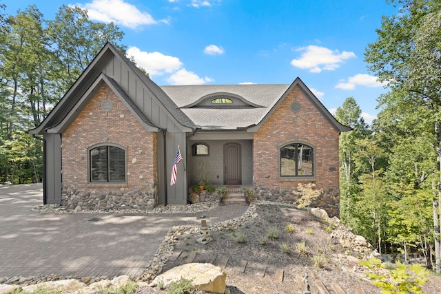 view of front of house with board and batten siding, brick siding, and roof with shingles