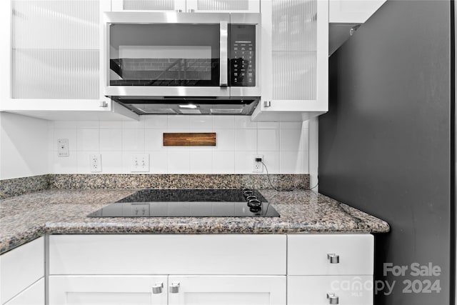 kitchen featuring black electric stovetop, decorative backsplash, white cabinetry, and stone counters