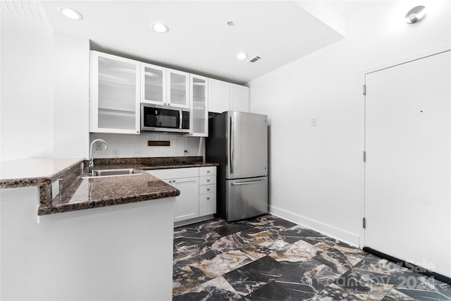 kitchen featuring dark stone countertops, stainless steel appliances, kitchen peninsula, and white cabinetry