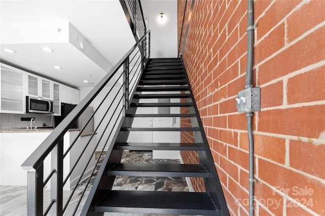 staircase featuring hardwood / wood-style floors and sink