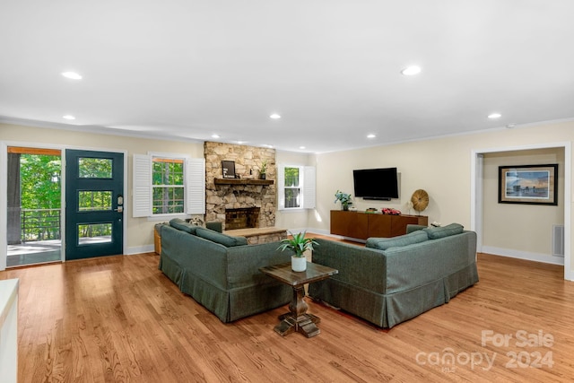 living room with a fireplace, light wood-type flooring, and ornamental molding