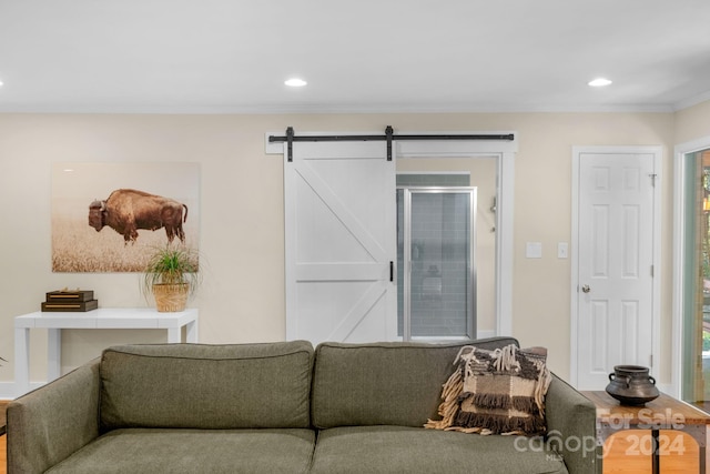 living room with a barn door, hardwood / wood-style flooring, crown molding, and a healthy amount of sunlight