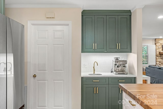 bar featuring wood counters, tasteful backsplash, crown molding, sink, and green cabinetry