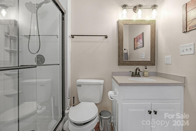 bathroom featuring toilet, a shower with door, and vanity