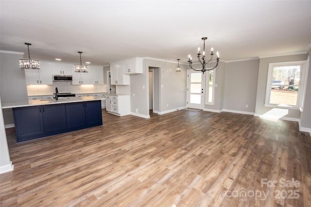 kitchen with sink, white cabinetry, ornamental molding, and hanging light fixtures