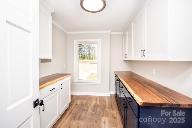 kitchen featuring white cabinets, light wood-type flooring, wooden counters, and crown molding