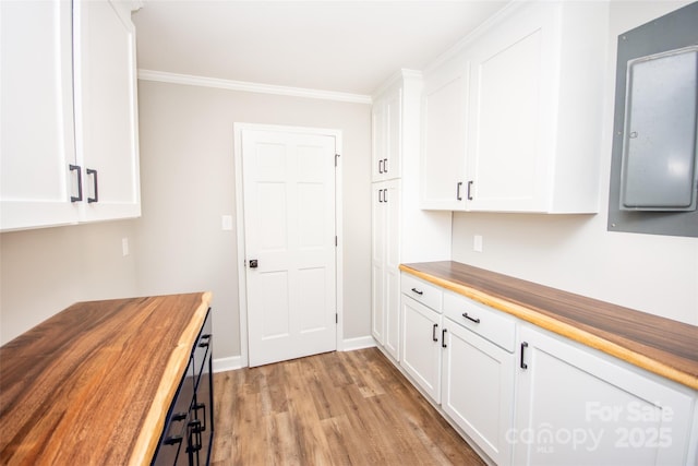 kitchen with white cabinetry, butcher block counters, crown molding, and light hardwood / wood-style floors