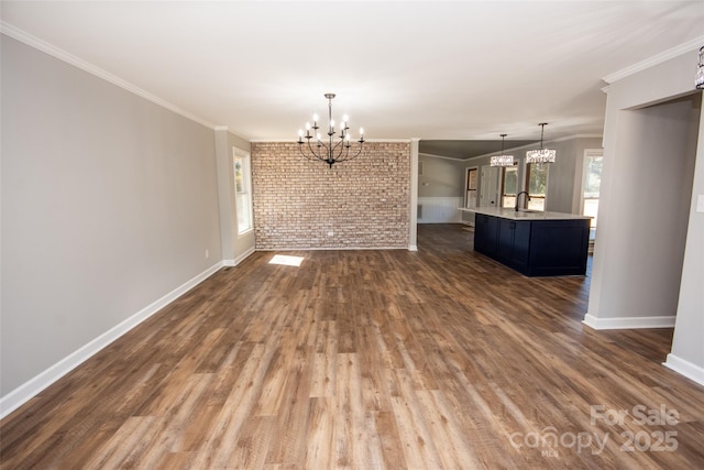 interior space with brick wall, sink, ornamental molding, an inviting chandelier, and dark hardwood / wood-style floors