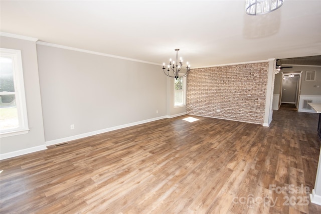 unfurnished dining area with wood-type flooring, ceiling fan with notable chandelier, brick wall, and crown molding