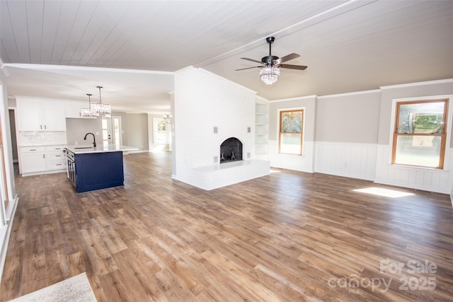 unfurnished living room featuring crown molding, sink, a fireplace, wooden ceiling, and ceiling fan with notable chandelier