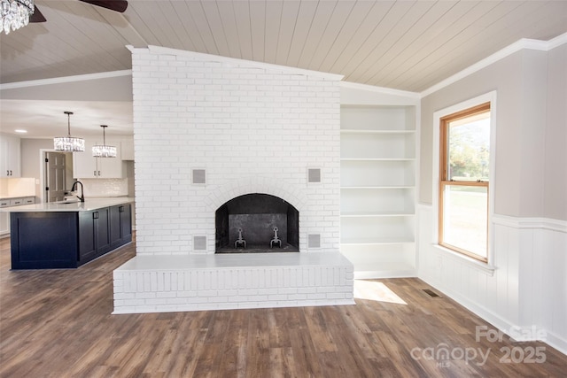 unfurnished living room featuring vaulted ceiling, a fireplace, sink, built in shelves, and ceiling fan