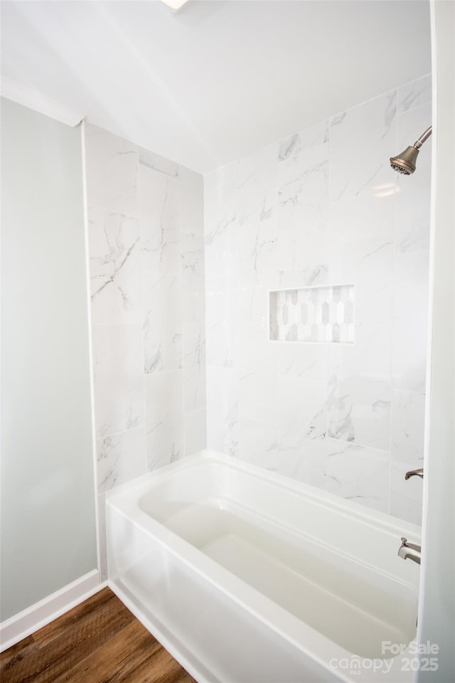 bathroom with hardwood / wood-style flooring and tiled shower / bath