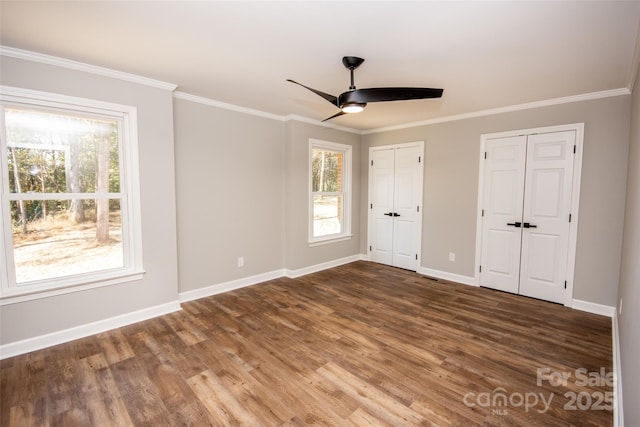 unfurnished bedroom with dark hardwood / wood-style floors, two closets, ceiling fan, and ornamental molding